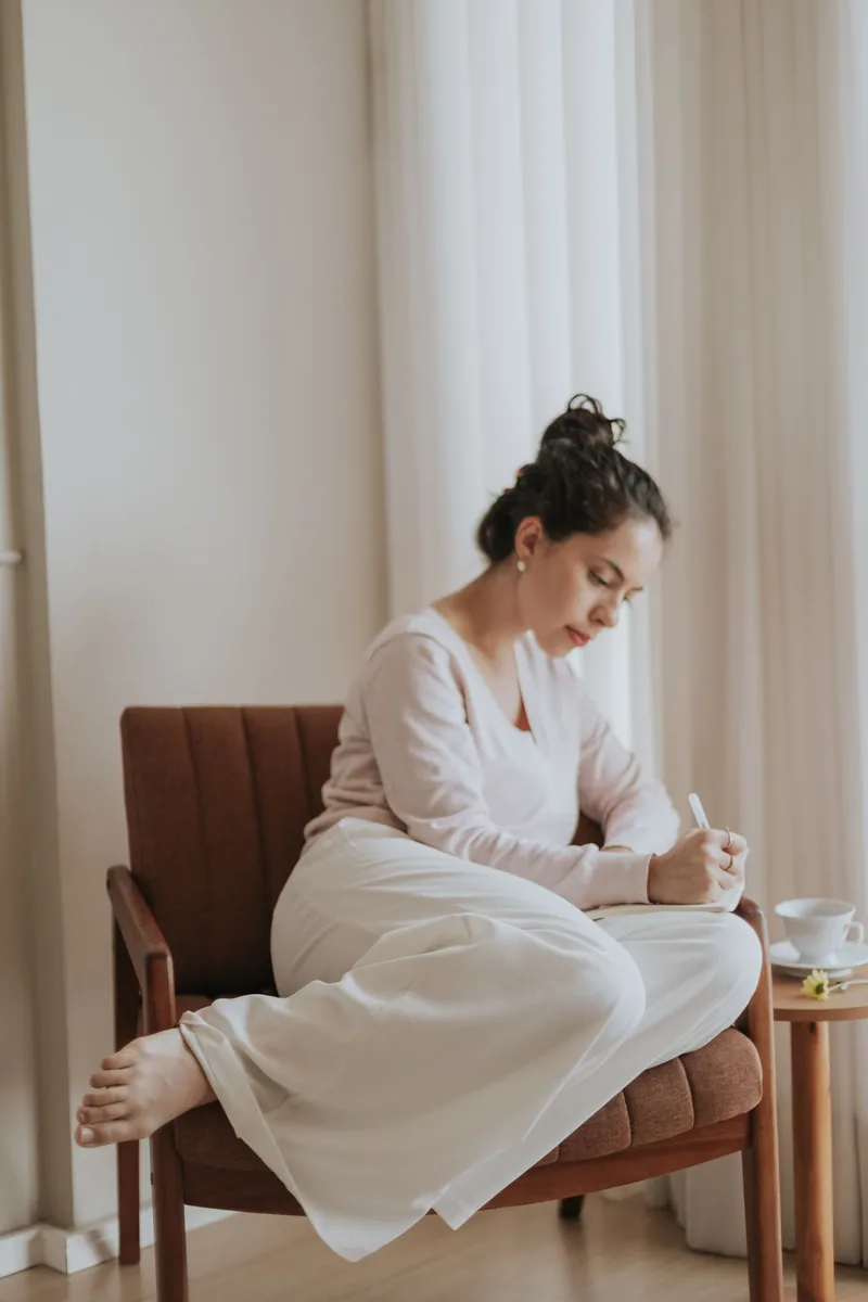 Woman journaling beside a sunlit window